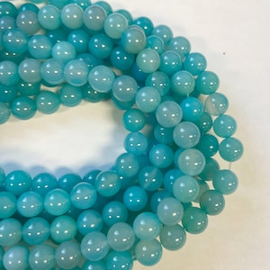 Op de afbeelding: Een streng ronde turquoise blauwe edelsteen kralen. De kralen zijn glad en hebben een lichte glans.