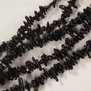 May include: Black irregular shaped beads made of natural black coral. The beads are strung together to form a long strand.