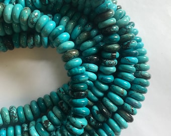 May include: A strand of turquoise beads, each bead is a light blue color with dark blue and black marbling. The beads are oval shaped and have a smooth, polished finish.