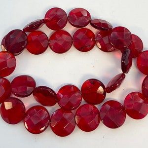 May include: A strand of red faceted gemstone beads. The beads are round and have a smooth, polished finish.