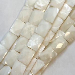 以下が含まれることがあります： 白い真珠のビーズのストランド。各ビーズはファセットカットされており、正方形の形をしています。