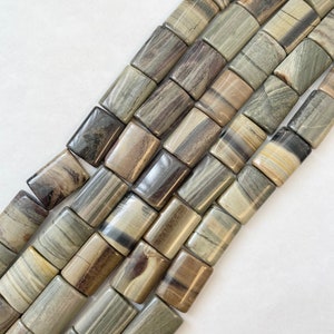 Può includere: Una collana di perline rettangolari in pietra levigata, di colore verde, marrone e grigio. Le perline presentano un motivo naturale striato.