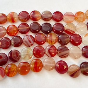 May include: A strand of round, flat agate beads with red, orange, and white swirling patterns. The beads are approximately 10mm in diameter.
