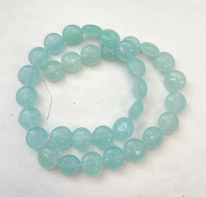 May include: A strand of light blue round beads with a slightly translucent finish. The beads are strung on a thin wire.