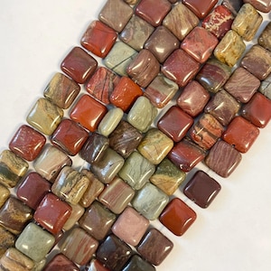 May include: A collection of square-shaped beads in various shades of red, brown, and green. The beads have a polished, smooth surface and are arranged in diagonal rows. The natural stone beads are ideal for jewelry making.