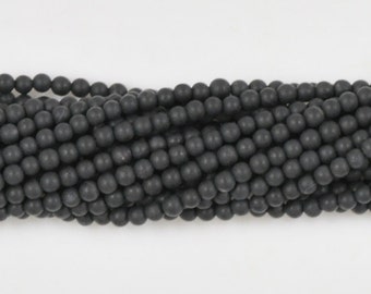 May include: A strand of black round beads. The beads are smooth and matte.