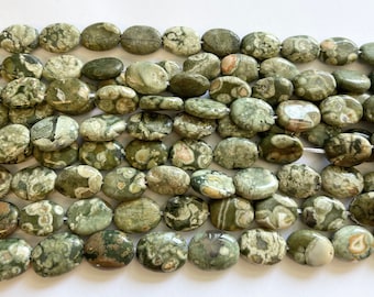 Pode incluir: Um fio de contas de jaspe ovaladas verdes e brancas. As contas têm um padrão manchado com manchas brancas e marrons.