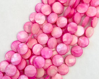 May include: A strand of pink and white shell beads. The beads are round and have a faceted finish.