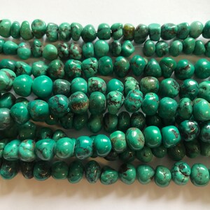 May include: A strand of turquoise beads, each bead is a unique, irregular shape and has a mottled green color.