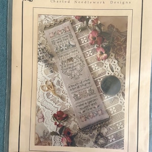 May include: A cross stitch pattern booklet titled The Drawn Thread Garden Recipe featuring a vertical sampler design with floral motifs and text including wild rose and flax, the columbine, a fragrant honeysuckle vine, a touch of mint, and a bit of thyme.