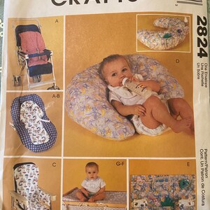 May include: A McCall's Crafts 2824 sewing pattern envelope featuring illustrations of baby accessories including a stroller liner, a nursing pillow, a high chair cover, and a hanging storage organizer with various fabric prints and patterns.