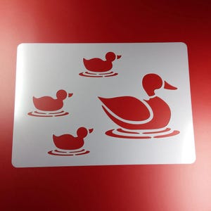 Könnte beinhalten: Eine weiße Schablone mit einem Design aus vier Enten. Die Enten sind in verschiedenen Größen und schwimmen in einem Teich. Die Schablone ist perfekt, um ein dekoratives Design auf einer Wand, Möbeln oder anderen Oberflächen zu erstellen.