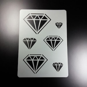 Könnte beinhalten: Eine hellgraue Schablone mit einem sich wiederholenden Muster aus schwarzen Diamantformen in verschiedenen Größen. Die Diamanten haben ein geometrisches Design. Die Schablone ist rechteckig.