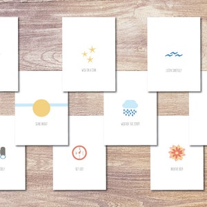 Puede incluir: Conjunto de 10 tarjetas imprimibles con ilustraciones y texto. Las tarjetas presentan una variedad de actividades con temática de campamento, como "Instalar el campamento", "Pedir un deseo a una estrella", "Escuchar atentamente", "Brillar", "Capear la tormenta", "Acurrucarse", "Mirar de cerca", "Perderse", "Respirar hondo", y "Abrazo secreto".