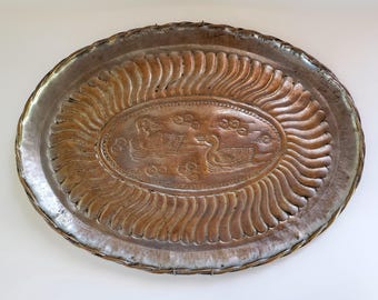 Puede incluir: Una bandeja ovalada de metal antiguo con un diseño en relieve detallado. La bandeja presenta un óvalo central con dos figuras de pájaros y un borde ondulado. El metal tiene un aspecto deslustrado y envejecido, lo que sugiere que es vintage. Aproximadamente 40 cm de largo.