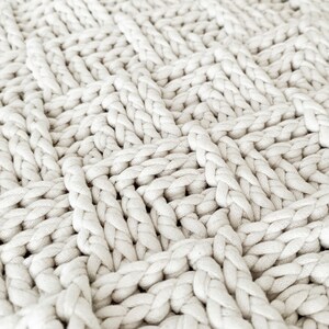 May include: Close-up of a white crocheted fabric with a textured, woven pattern.