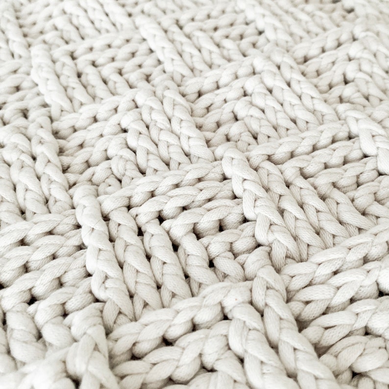 May include: Close-up of a white crocheted fabric with a textured, woven pattern.