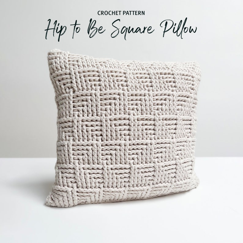 May include: A crocheted square pillow in a light beige color. The pillow has a woven pattern and is made with a thick yarn.
