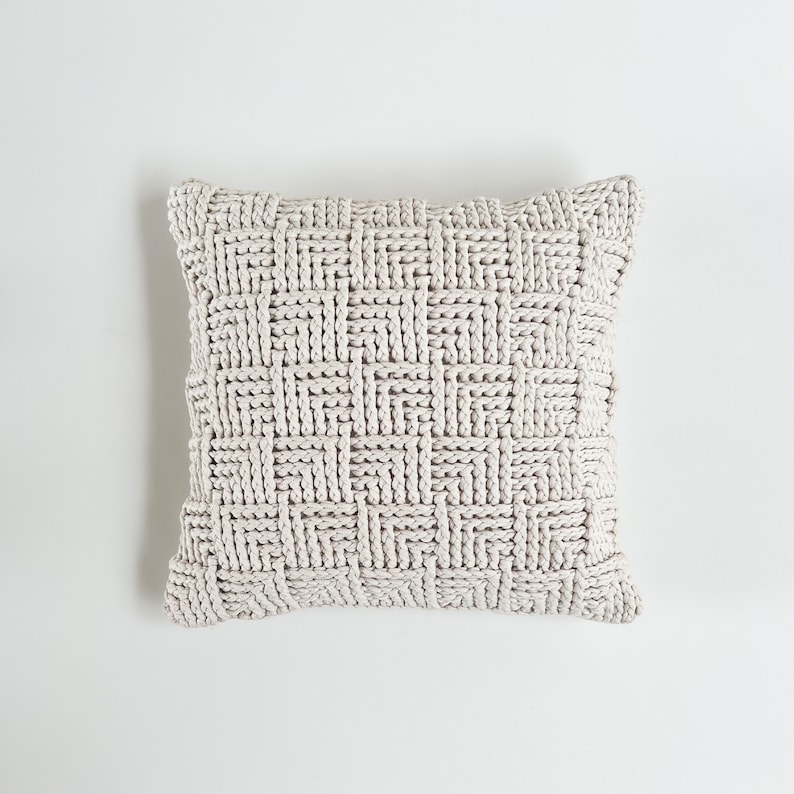 May include: A white knitted throw pillow with a woven pattern.