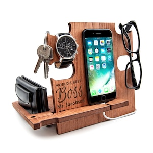 Può includere: Supporto per telefono in legno con un porta orologio, un gancio per le chiavi e un porta occhiali. Ha il testo "World's Best Boss Mr. Jacobson" inciso sul davanti.