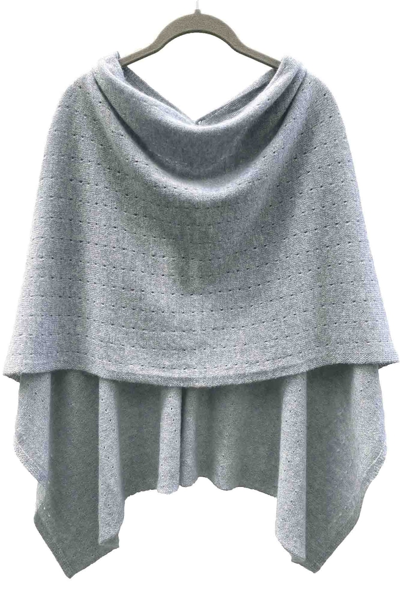 May include: A light gray knitted poncho with a cowl neck and a delicate openwork pattern.
