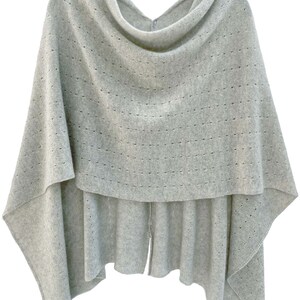 May include: A gray knitted poncho with a cowl neck and a delicate openwork pattern.