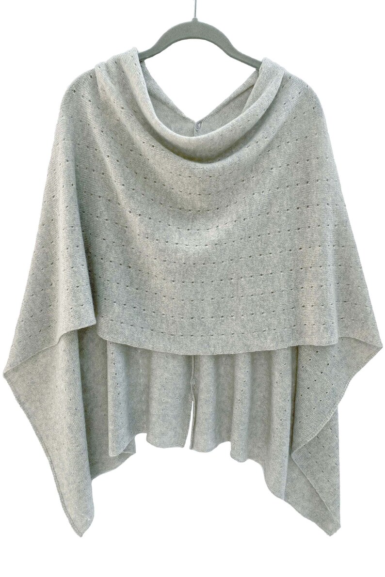 May include: A gray knitted poncho with a cowl neck and a delicate openwork pattern.
