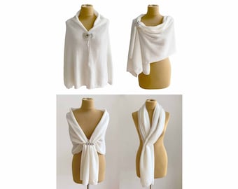 Puede incluir: Cuatro chales de punto blanco expuestos en maniquíes. Cada chal está estilizado de forma diferente, mostrando varias formas de llevar la prenda. Los chales están hechos de una tela suave y ligera y presentan un delicado patrón de tejido abierto.