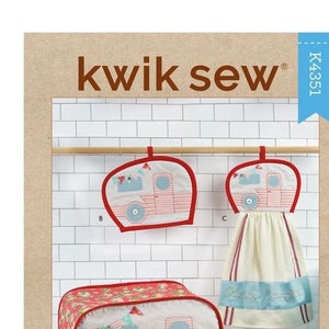 May include: Kwik Sew kitchen accessories set featuring a camper design. The set includes a toaster cover, oven mitt, and a hanging towel. The camper is pink and blue with red trim. The words "Kwik Sew" and "Kitchen Accessories" are visible.