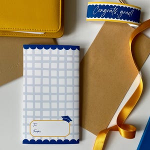 May include: A graduation gift set with a blue and white patterned card, a "Congrats, grad!" tag, a yellow ribbon, and a yellow wallet. The card has space for "To" and "From".