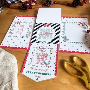 May include: Christmas-themed greeting cards with red and black polka dot borders, featuring illustrations of a reindeer, Santa Claus, and the text "Merry Christmas." The cards are displayed on a wooden surface with decorative elements.