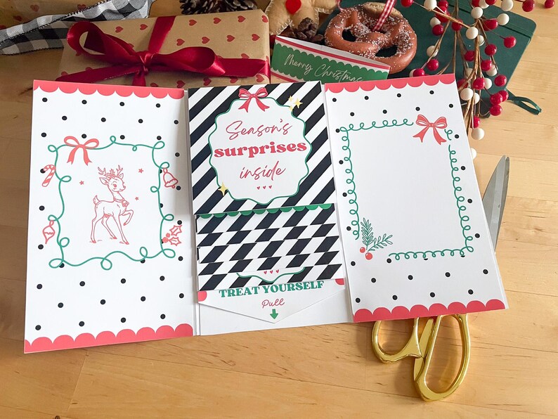 May include: A festive Christmas card with a pink scalloped edge, black polka dots, and a reindeer illustration. The card reads "Season's surprises inside" and "Treat Yourself, Pull". A pair of gold scissors is on the wooden surface.