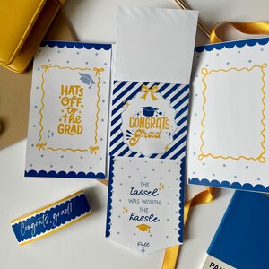 May include: A graduation-themed stationery set in blue and yellow. The set includes cards with phrases such as "Congrats Grad" and "Hats off to the Grad." A ribbon and a blue Pantone colour swatch are also visible.