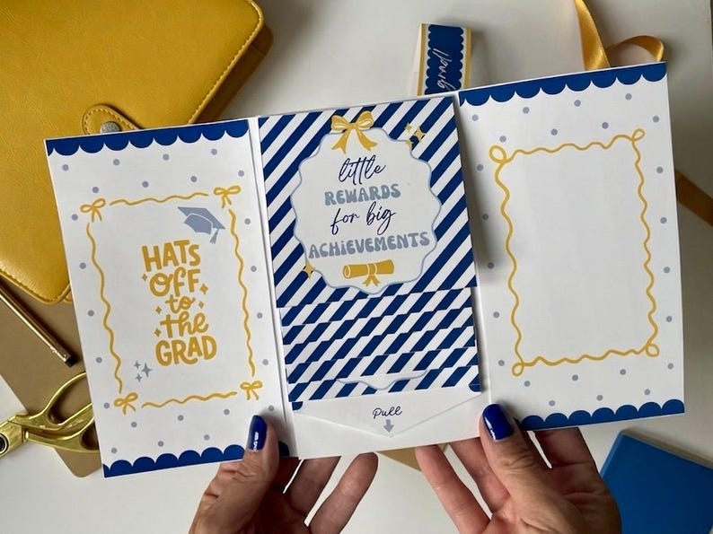 May include: A graduation card with a blue and white design. The card says "Hats off to the Grad" and "Little rewards for big achievements". The card has a pull tab and a yellow bow.