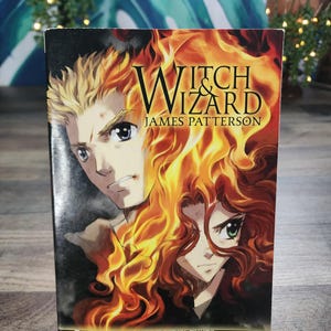 Könnte beinhalten: Ein Taschenbuch mit dem Titel "Witch & Wizard" von James Patterson. Das Cover zeigt zwei illustrierte Charaktere, einen mit blonden Haaren und einen mit roten Haaren, vor einem Hintergrund aus Flammen. Das Buch ist Band 1 der Serie.