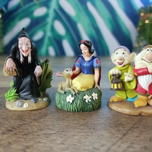 Könnte beinhalten: Eine Sammlung von Disney-Figuren mit Charakteren aus Schneewittchen und den sieben Zwergen. Das Set beinhaltet die böse Königin, Schneewittchen mit einem Reh und zwei Zwergen. Die Figuren sind farbenfroh und detailliert, ideal für Sammler.
