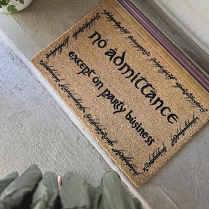 以下が含まれることがあります： 黒い筆記体で「No admittance except on party business」と書かれた茶色の玄関マット。テキストは黒い筆記体の装飾的な境界線で囲まれています。