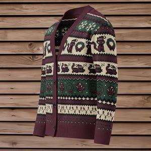 May include: Burgundy cardigan sweater with a festive pattern. The design includes snowflakes, squirrels, wreaths, and sleeping train cars. The sweater has a V-neck and button closure. The background is a wooden surface.