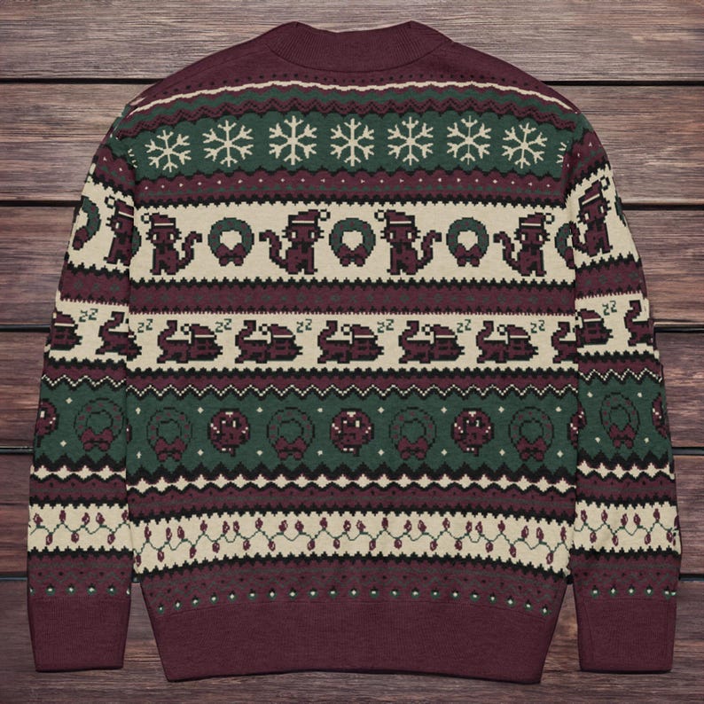 May include: A burgundy Christmas sweater with a festive pattern. The design includes snowflakes, Santa hats, wreaths, and other holiday-themed elements in green, white, and burgundy. The sweater has a crew neck and long sleeves.