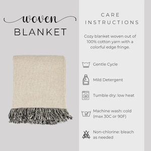 May include: A woven blanket with a neutral color scheme, featuring a cream-colored body and a black and white fringe. The text "woven BLANKET" is at the top left. Care instructions are also included.