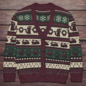 May include: Burgundy cardigan sweater with a festive holiday pattern. The design includes snowflakes, wreaths, and pixelated images of a train and a squirrel. The sweater has a V-neck and button closure.