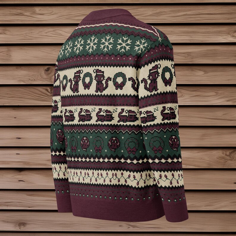 May include: Burgundy Christmas sweater with a festive pattern. The design includes snowflakes, wreaths, and pixelated images of cats wearing Santa hats. The sweater has a ribbed neckline, cuffs, and hem, and is made of a soft knit material.