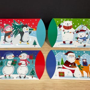 May include: Four Christmas gift boxes with rounded ends. Each box features a different winter scene: penguins with a tree, polar bears with lights, snowmen with gifts, and Santa with a reindeer. The boxes have red, green, and blue accents.