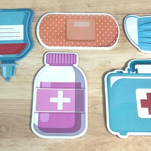 May include: A set of six medical-themed stickers featuring a purple syringe, a blue IV bag, an orange adhesive bandage with white dots, a blue face mask, a purple medicine bottle with a white cross, and a blue first aid kit with a red cross.