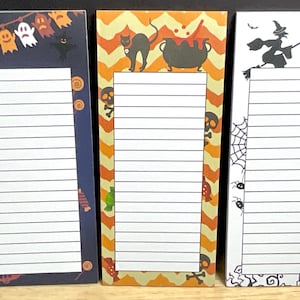 May include: Three Halloween-themed notepads with lined pages. The first features ghosts and candy, the second a black cat and cauldron, and the third a witch and haunted house. Each notepad has a decorative border.