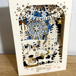 Carte Joyeux Noël découpée au laser , Feuille d'or , Arbre , Vacances , Festif , Grande roue , Neige , Étoiles , Nuit , Joie , Église