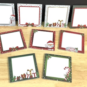 May include: A collection of eight square sticky note pads featuring various Christmas-themed borders. Designs include illustrations of snowmen, Santa Claus, wrapped gift boxes, candy canes, holly, and the text Merry Christmas on red and green backgrounds.