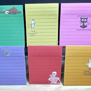 May include: A collection of six colorful sticky note pads with humorous illustrations and text. The pads are green, yellow, pink, purple, red, and orange. Each pad has a different design, including a sloth, a person with back pain, a cat, a skeleton hand, a skeleton, and a goose.