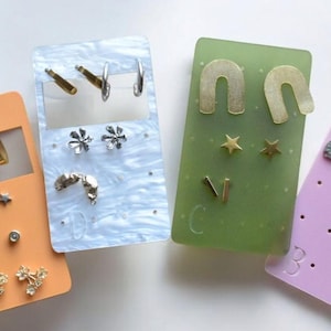 Könnte beinhalten: Eine weiße Keramik-Tasse mit schwarzem Henkel und dem Text "But First, Coffee" in fetter, schwarzer Schrift. Die Tasse steht vor einem verschwommenen Hintergrund, der eine gemütliche Umgebung andeutet.