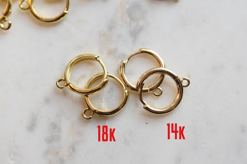 Puede incluir: Dos pares de pendientes de aro de oro, un par etiquetado como "18K" y el otro como "14K".